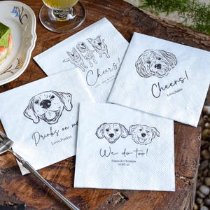 May include: White square napkins with black line drawings of dogs and text. One napkin says "Cheers! Love, Sadie", another says "Drinks on me Love, Parker", and another says "We do too! Diana & Christian 10/07/23".