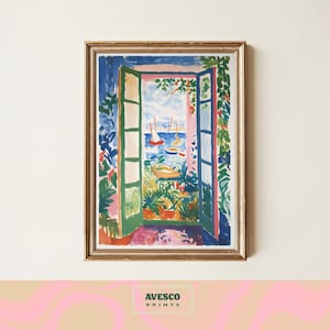 May include: A framed art print depicting a vibrant coastal scene. The artwork showcases an open window overlooking a blue sea with sailboats. The window frame is green, and the surrounding foliage is a mix of green, red, and blue. The print is framed in a gold-colored frame. The text "AVESCO PRINTS" is at the bottom.