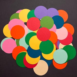 May include: A collection of colorful paper circles in various shades of pink, red, orange, yellow, green, blue, and purple. The circles are arranged in a random pattern, creating a visually appealing and vibrant display.