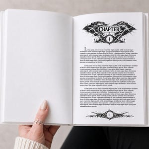 Könnte beinhalten: Ein offenes Buch mit weißem Einband, gehalten von einer Person. Die rechte Seite zeigt das Wort "CHAPTER" über einem dekorativen Design und die Zahl "1". Der Text ist schwarz, mit dekorativen Elementen. Die linke Seite ist leer.