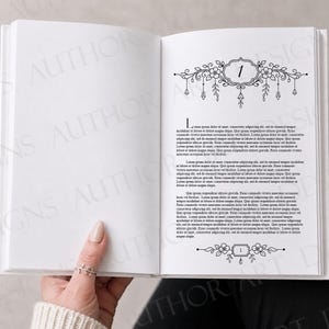 May include: An open book with white pages featuring black printed text and decorative floral illustrations at the top and bottom of the page. The top header includes the number 1 enclosed in an ornate frame with hanging floral elements.