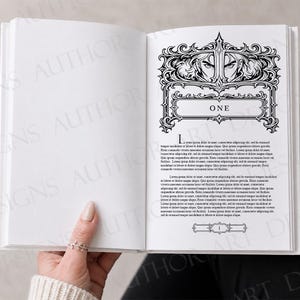 May include: An open book displaying a chapter heading page with black ink illustrations. The top features an ornate frame with a pair of eyes, the word ONE in a central box, and a decorative footer. The text is in Latin, printed on white paper.