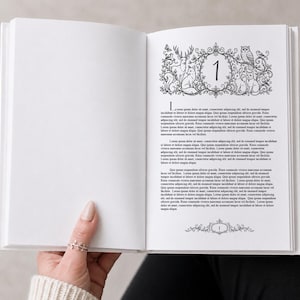 Könnte beinhalten: Ein offenes Buch mit weißem Einband, gehalten von einer Person. Die rechte Seite zeigt eine Schwarz-Weiß-Illustration von Waldtieren um die Zahl 1. Text befindet sich unter der Illustration und am unteren Rand.
