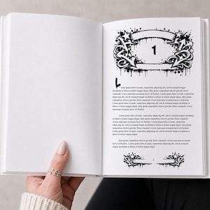 May include: An open book with a white cover and pages. The right page features a black and white graphic design with the number "1" inside a banner, surrounded by stars and arrows. The page also contains lines of text.
