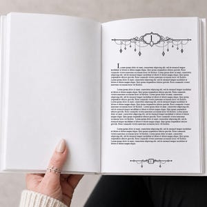 Könnte beinhalten: Ein offenes Buch mit weißen Seiten, gehalten von einer Hand mit einem Ring. Der Text ist schwarz, mit dekorativen schwarzen Linienzeichnungen oben und unten auf der Seite. Der erste Buchstabe des Textes ist ein großes, stilisiertes "L".