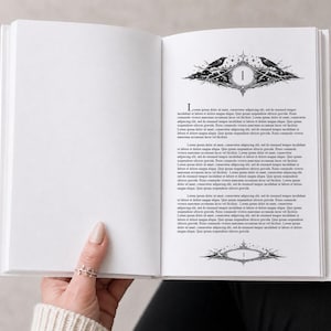 Könnte beinhalten: Ein offenes Buch mit weißen Seiten, gehalten von einer Hand. Die linke Seite ist leer, während die rechte Seite dekorative schwarze Illustrationen von Vögeln und verzierten Rahmen sowie Text enthält. Die Zahl "1" wird in der Mitte der Seite angezeigt.