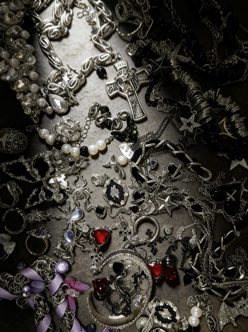 Puede incluir: Una variedad de joyas plateadas, que incluyen collares, anillos y pendientes. La colecci&oacute;n presenta varios dise&ntilde;os, como cruces, estrellas y colgantes en forma de coraz&oacute;n, con acentos de piedras preciosas negras y rojas y perlas.