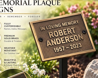 May include: A rectangular bronze-colored memorial plaque mounted on a black metal stake. The plaque features raised lettering that reads IN LOVING MEMORY ROBERT ANDERSON 1957-2023. A circular inset shows the back of the plaque with a metal mounting bracket.