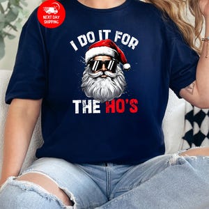 May include: A navy blue t-shirt with a white graphic of Santa Claus wearing sunglasses and the text "I do it for the ho's".