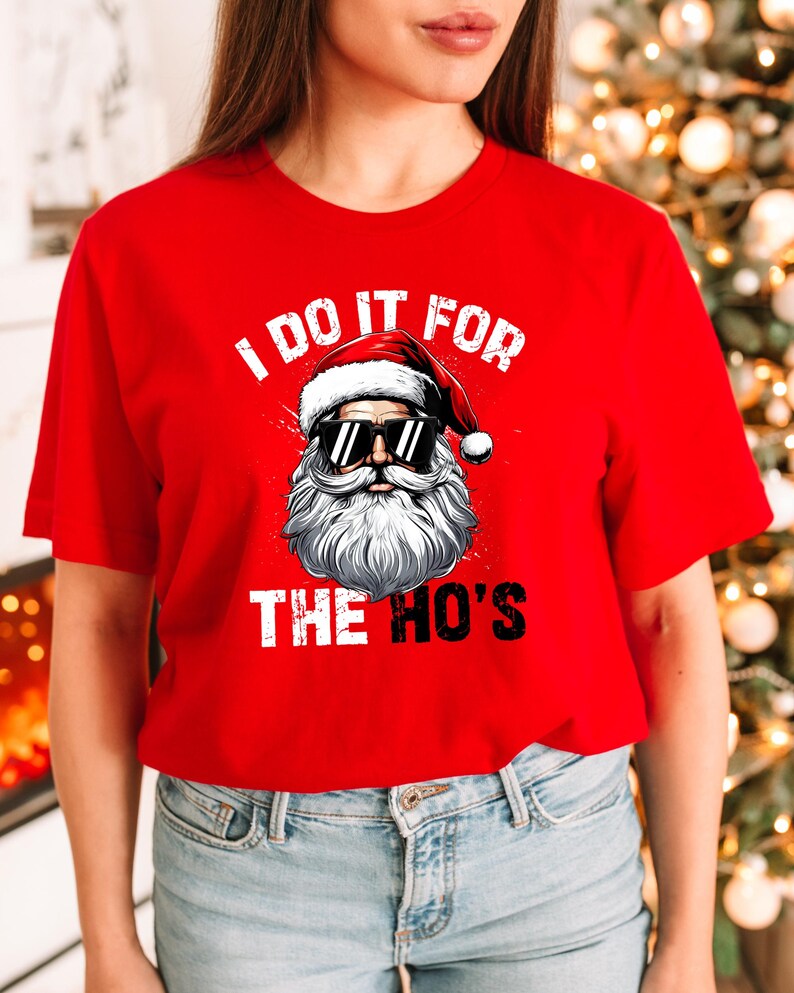 May include: Red t-shirt with a white graphic of Santa Claus wearing sunglasses and the text "I do it for the ho's".