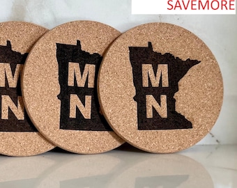 Puede incluir: Tres posavasos redondos de corcho con un contorno marrón oscuro del estado de Minnesota y las letras "MN" en el centro. El texto "Use promo code: SAVEMORE" es visible.