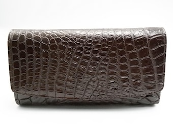 May include: A dark brown crocodile embossed leather wallet.