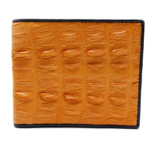 May include: A bi-fold wallet with a textured, crocodile-like pattern in a warm, golden-brown hue. The wallet has a black border and a rectangular shape. The design suggests a focus on style and functionality.