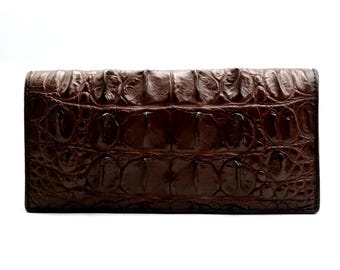 May include: A brown crocodile leather wallet with a textured pattern.