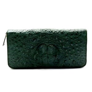 May include: A dark green, textured wallet with a zip closure. The wallet has a reptile-like embossed pattern. The wallet is rectangular and appears to be made of leather.