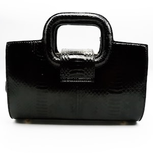 May include: A black leather handbag with a distinctive top handle. The bag features a textured, snakeskin-like pattern.