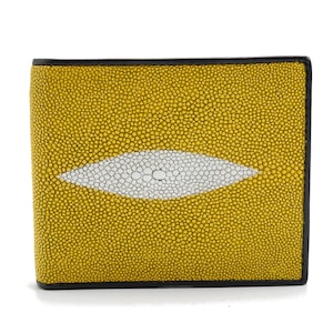 May include: Yellow stingray leather wallet with a white eye-shaped design. The wallet has a black border and a textured surface. The design is centered on the front of the wallet.