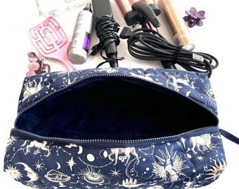 May include: A navy blue quilted makeup bag with a zipper closure. The bag is decorated with a white print of celestial constellations, stars, and moons.