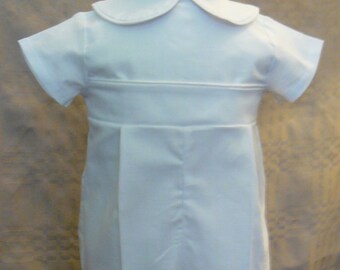 May include: White short-sleeved outfit with a Peter Pan collar and a pleated front. The outfit is made of a smooth, white fabric.