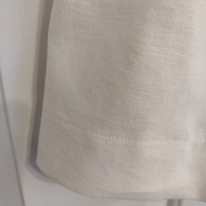 May include: White linen fabric with a subtle texture and a single row of stitching along the bottom edge.