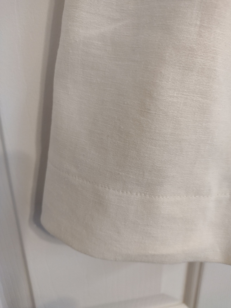 May include: White linen fabric with a subtle texture and a single row of stitching along the bottom edge.