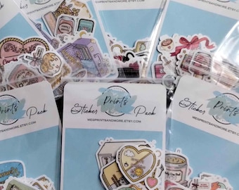 May include: A collection of sticker packs in clear plastic bags. Each pack has a light blue backing card with the words "Sticker Prints Pack" and the Etsy shop's URL. The stickers feature various colorful illustrations.