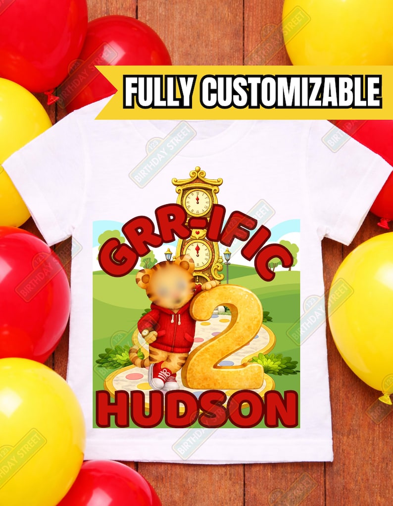 May include: White t-shirt with a colorful graphic featuring a cartoon tiger, the word "GRR-IFIC", the number "2", and the name "HUDSON". The shirt has the text "FULLY CUSTOMIZABLE" across the top. Balloons in red and yellow surround the shirt.