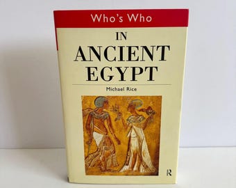以下が含まれることがあります： マイケル・ライス著「Who's Who in Ancient Egypt」というタイトルの本。クリーム色の表紙に赤いアクセントがあり、古代エジプトの衣装を着た2人の人物のイラストが描かれています。本は直立しています。