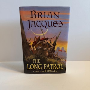 Könnte beinhalten: Ein Hardcover-Buch mit dem Titel "The Long Patrol" von Brian Jacques. Das Cover zeigt anthropomorphe Kaninchen in Militäruniform vor einem Sonnenuntergang. Das Buch ist eine Geschichte aus Redwall.