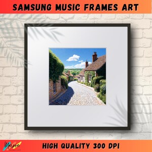 Könnte beinhalten: Ein gerahmtes Foto einer malerischen, steingebauten Dorfstraße mit einem Kopfsteinpflasterweg, der zu einer Reihe von Häusern mit üppigem Grün führt. Die Häuser haben rote Ziegeldächer und sind von lebendigem Grün umgeben.