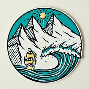 May include: Circular sticker featuring a nautical scene. A yellow sailboat sails on turquoise waves, with white-capped mountains in the background. A yellow sun shines above the mountains, all within a teal border.