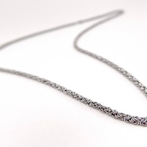 May include: A silver chain necklace with a byzantine style chain.