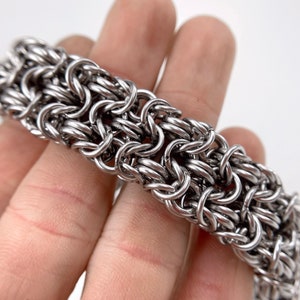 Peut inclure: Un bracelet en maille argentée avec un motif tissé.