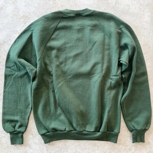 K&ouml;nnte beinhalten: Ein dunkelgr&uuml;ner Pullover mit Rundhalsausschnitt und langen &Auml;rmeln. Der Pullover hat eine klassische, lockere Passform.
