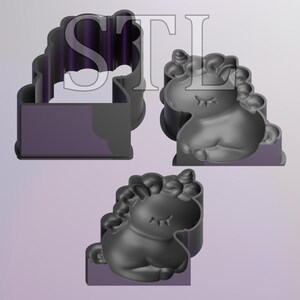 May include: Three dark gray unicorn-shaped cookie cutters. The unicorn has a closed-eye design and a curly mane. The cutters are on a light purple background. The letters "STL" are in the background.