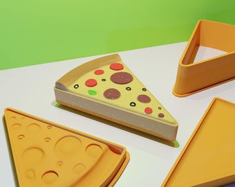 May include: Three yellow plastic pizza slice molds. One slice is topped with red and green toppings, and the other two are plain.