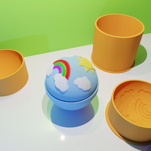 May include: A blue bath bomb with a rainbow, clouds, and sun design, sitting next to three orange containers. The bath bomb has a light blue base and a white and colorful design. The containers are cylindrical and have a smooth surface.