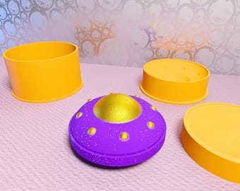 May include: A purple and gold toy spaceship with yellow accents and several yellow, cylindrical, and circular objects. The spaceship has a gold dome and is surrounded by yellow objects of varying sizes and shapes. The objects are on a pink, textured surface.