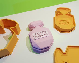 May include: Three orange plastic cookie cutters in the shape of perfume bottles. One cutter has the words "EAU DE PARFUM" on it. The other two cutters are blank.