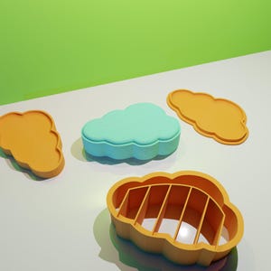 May include: Four cloud-shaped cookie cutters, two are orange and two are yellow. One of the orange cutters has a detailed interior design.