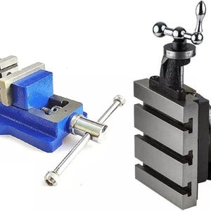 May include: A blue metal machine vise with a silver handle and two jaws, positioned next to a black tilting angle plate featuring a silver T-slotted surface and a chrome-plated adjustment handle with a graduated scale for precise positioning.
