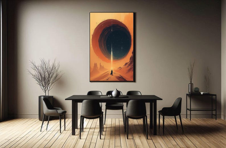 May include: A black and white abstract art print featuring a large circle in the centre. The circle is filled with a dark blue colour and has a white line running through it. The background is a light orange colour. The print is hanging on a wall in a dining room with a black table and chairs.