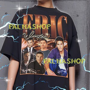 May include: Black oversized t-shirt featuring a graphic of several men and the text "ERIC Winter PALMASHOP". The shirt has a crew neck and short sleeves. The text "PALMASHOP" is also printed on the bottom of the graphic. The model is wearing an XL shirt.