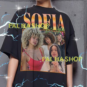 May include: Black oversized t-shirt with a graphic featuring the word "SOFIA" in gold and a photo collage of four women. The shirt also has the text "PALMASHOP" in green and gold.