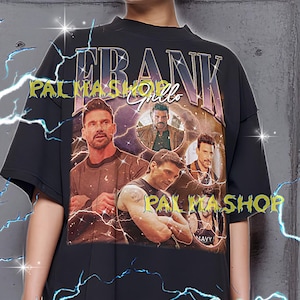 May include: Black oversized t-shirt featuring a graphic of Frank Grillo with the text "FRANK" above the image. The shirt also has the text "PALMA SHOP" in a stylized font. The model is wearing a XL shirt.