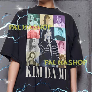 May include: Black unisex t-shirt featuring a grid of images of Kim Da-Mi and the text "KIM DA-MI" in white. The shirt also has the text "PALMASHO" in a yellow font. The model is wearing an XL shirt.