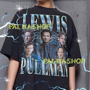 Puede incluir: Camiseta negra de gran tamaño con un gráfico de varios hombres y el texto "LEWIS PULLMAN PALMASHOP". El diseño incluye gráficos de rayos. La camiseta tiene cuello redondo y mangas cortas. El texto está en una fuente estilizada.