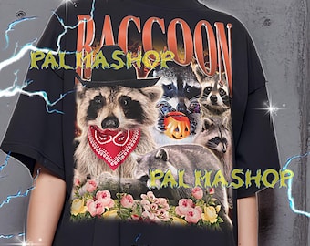 Peut inclure: T-shirt noir avec un motif de raton laveur et le mot "RACCOON" en orange. Le motif comprend des ratons laveurs portant des chapeaux et des bandanas, avec des fleurs. Le texte "PALMASHOP" est également visible.