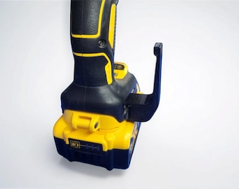 Può includere: Un elettroutensile nero e giallo con un accessorio nero attaccato. L'utensile ha una base gialla e un'impugnatura nera con dettagli gialli. L'accessorio è un attacco nero a forma di gancio.