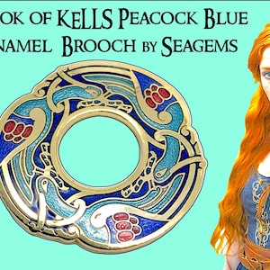 May include: A circular enamel brooch with a gold-tone border, featuring intricate blue, teal, and red designs. The brooch is labeled "Book of Kells Peacock Blue Enamel Brooch by Seagems."